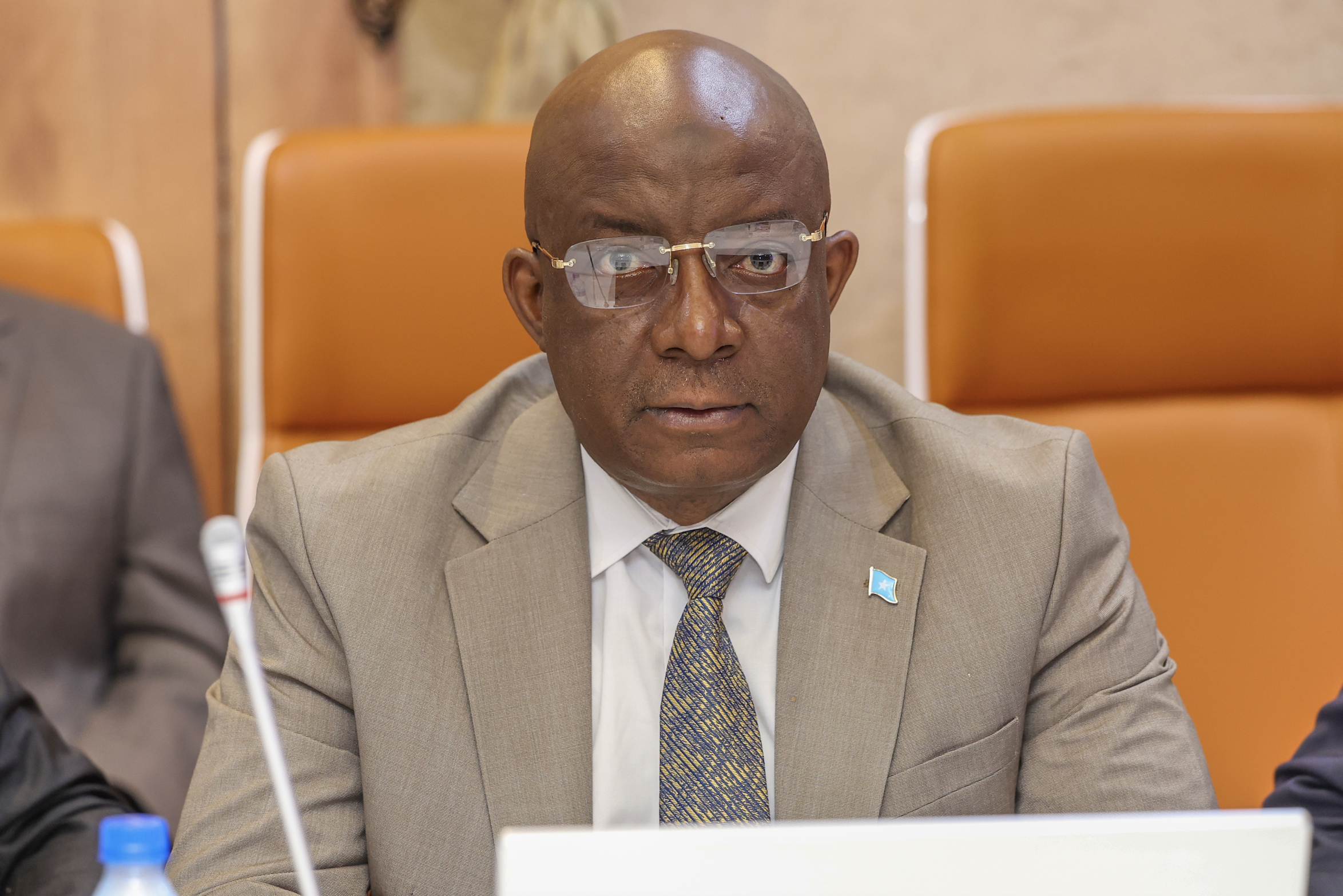 Somalia’s Minister of Information, Culture, and Tourism sits in a Cabinet meeting with a Somali flag pin on his lapel.